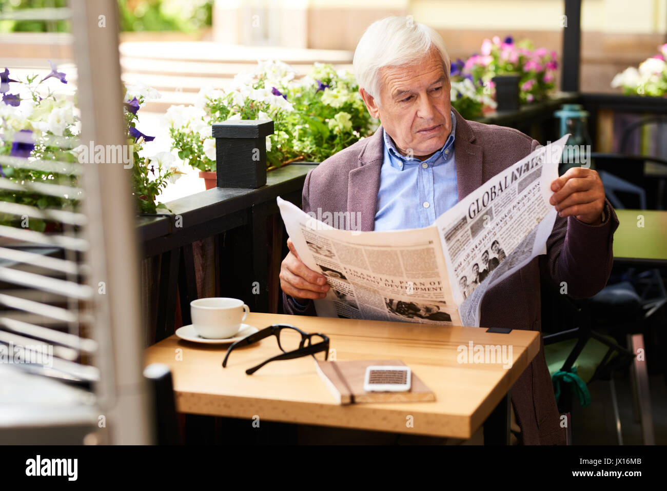 Portrait des modernen älterer Mann lesen Zeitung im Cafe im Freien genießen, sonnigen Morgen im Ruhestand Stockfoto