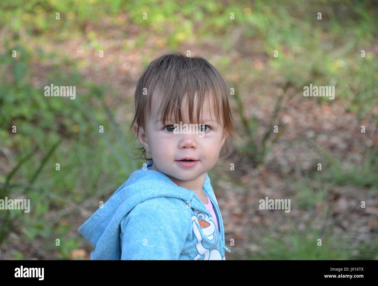 Ein weibliches Kind in einem blauen Anzug zu Fuß durch die bewaldeten Park. Stockfoto