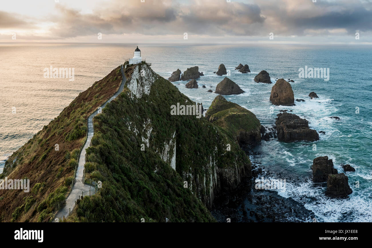 Sonnenaufgang am Nuggets Leuchtturm, die Catlins, Neuseeland. Schöne Landschaft mit gefährlichen Felsen und stürmischen Wolken im Hintergrund. Stockfoto