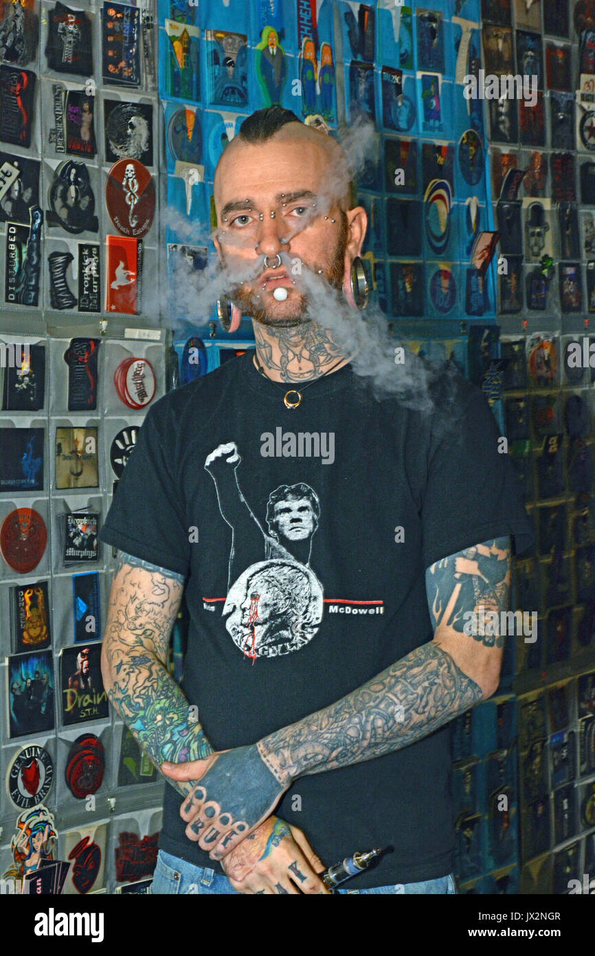 Porträt eines Mannes mit einer Tattoo Convention, die in den Tätowierungen bedeckt ist, und wegen seiner Piercings, können Schlag aus seiner Nase in 4 Plätze rauchen. Stockfoto