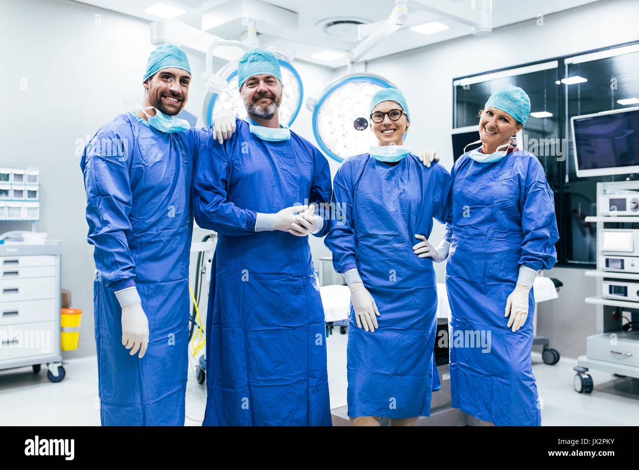 Portrait von erfolgreichen medizinischen Arbeiter in chirurgischen Uniform im Operationssaal. Team von Chirurgen im Operationssaal, bereit für die nächste Operation. Stockfoto