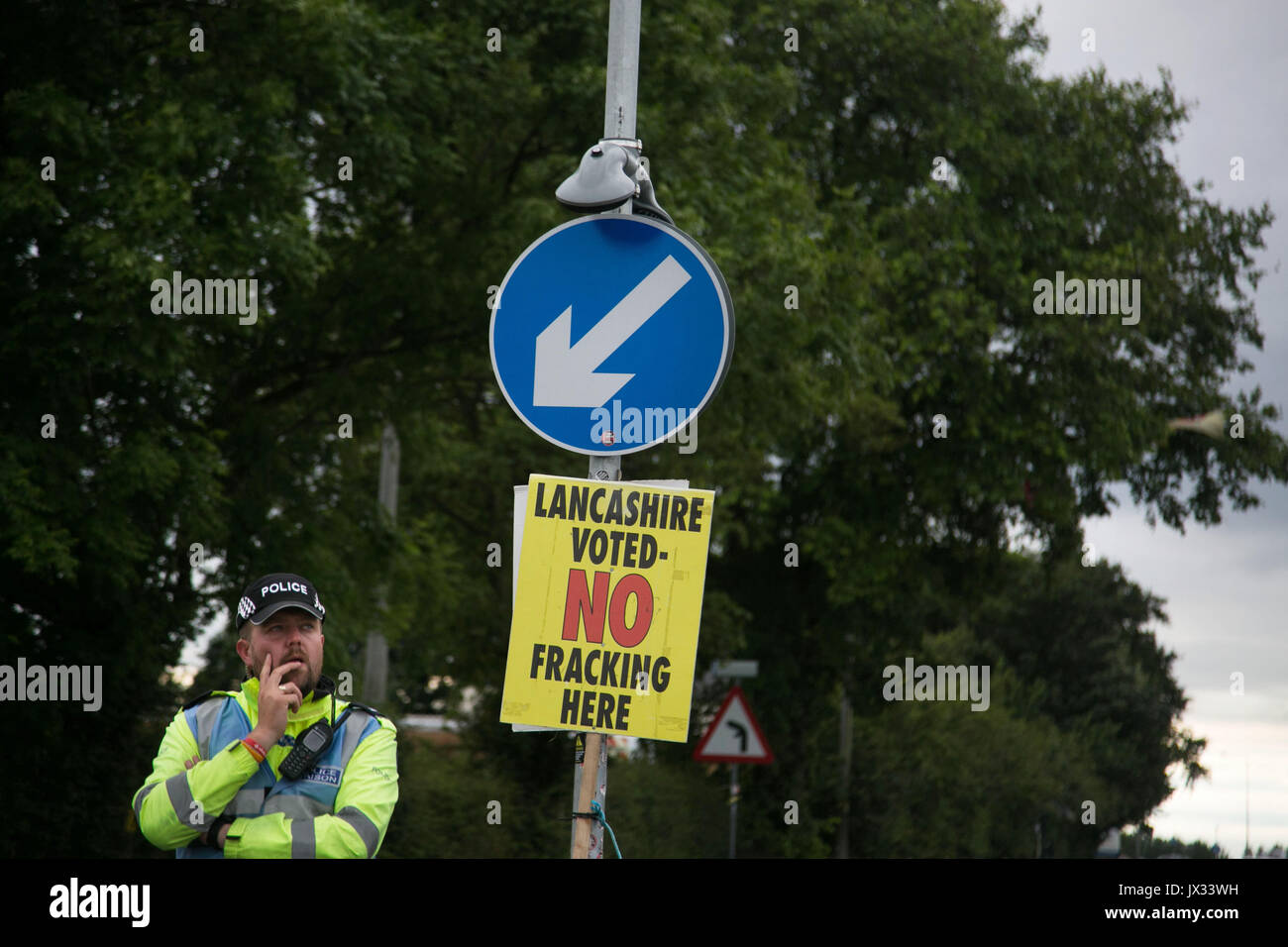 Ein Polizist stand unter einer anti-fracking Zeichen durch die Tore von Quadrilla fracking Website in Lancashire. Stockfoto