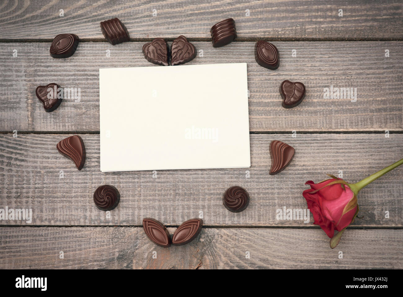 Stück Papier, Schokolade und eine einzelne Rose Stockfoto