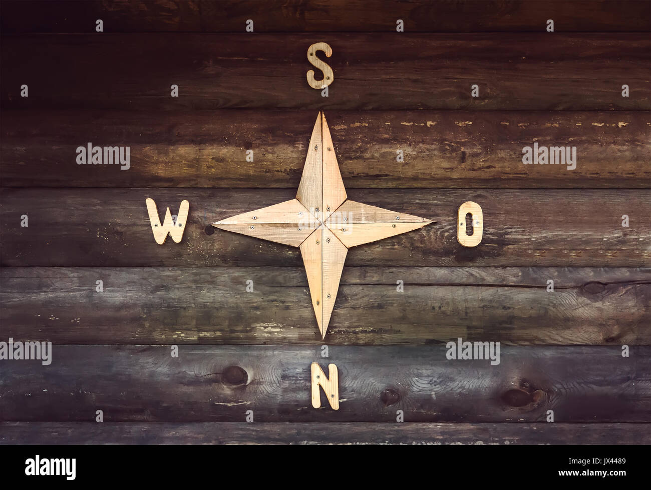 Holz- Kompass auf eine Holzwand in einem Landhaus. Dekorierte Wand in Form einer Kompass, mit den Teilen der Welt, Nord, Süd, West, Eas Stockfoto