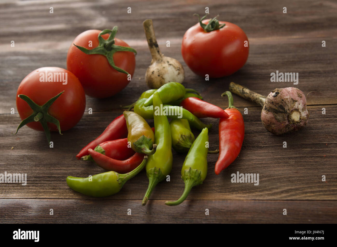 Rote Tomaten Reife, hot chili peppers, auf einem Holztisch Knoblauch Stockfoto