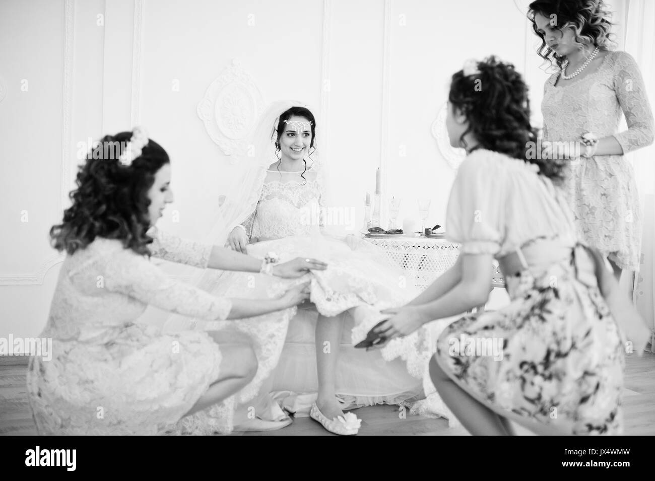 Brautjungfern helfen Braut ihren Schuhe auf und machen Sie sich bereit für ihre Hochzeit. Schwarz-weiß Foto. Stockfoto