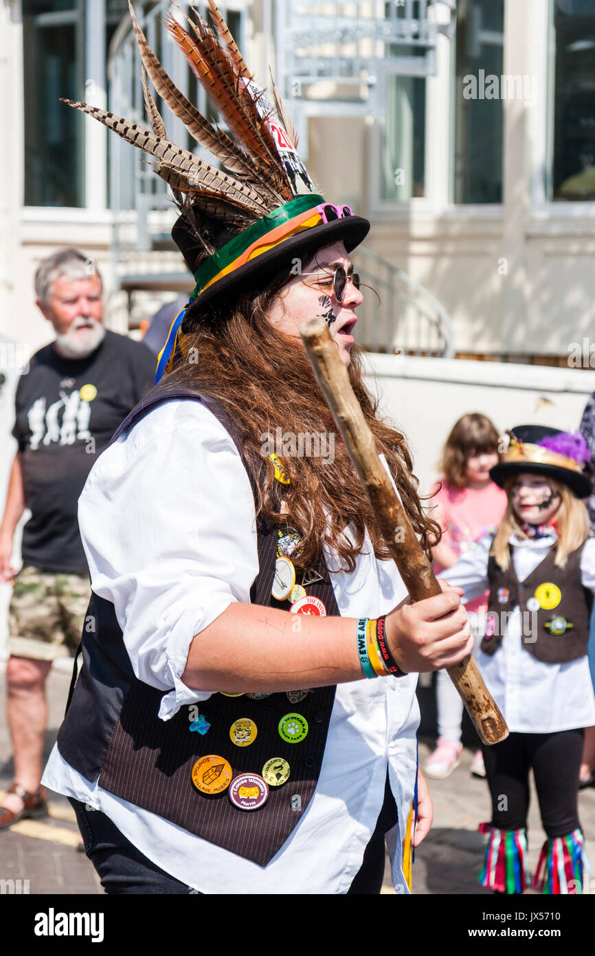 Junge Frauen, die in ihrem 20s, Volkstänzer, Tanzen mit Morris Seite, Dead Horse Morris, während der broadstairs Folk Woche. Mit Sonnenbrille und schwarzem Hut mit Feder, und halten ein Pole beim Tanzen. Stockfoto