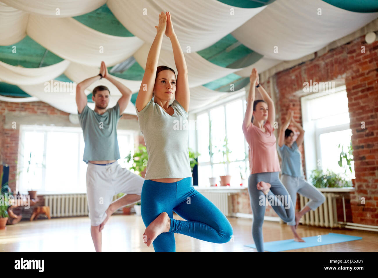 Gruppe von Menschen, die Yoga die Baumhaltung im Studio Stockfoto