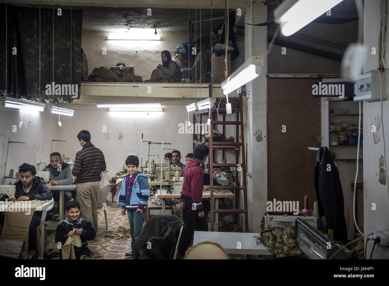 Einige der Unzähligen syrische Flüchtlinge Kinder arbeiten in Fabriken, die in der ganzen Türkei, jetzt nach Hause zu über 2,7 Millionen Syrer. Die kleine Textil shop, wo er und andere Jungen, Mädchen und Männer beschäftigt sind produziert Uniformen und Rucksäcke, die an den verschiedenen kriegführenden Parteien in Syrien verkauft werden. Die Armut treibt viele Familien ihre Kinder zur Arbeit anstatt zur Schule. Bildungschancen für die Syrer in der Türkei sind auch begrenzt. Stockfoto