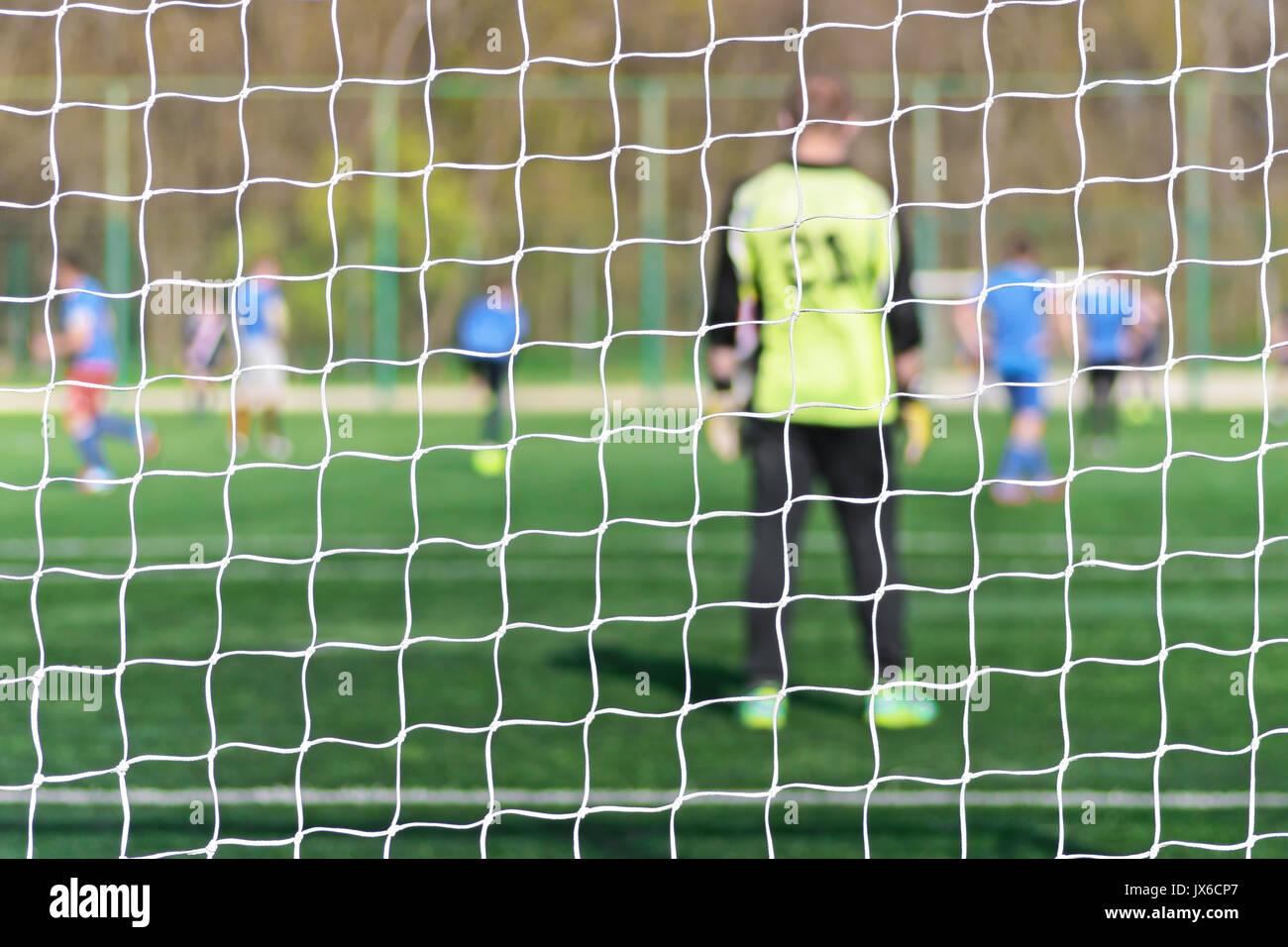 Torhüter steht gegen Ziel mit Net und Stadion. Fußball Tor net. Fußball Tor net. In verschwommenen Hintergrund stehen einem Torwart. Hinter dem Ziel der Spielgeschehen Stockfoto