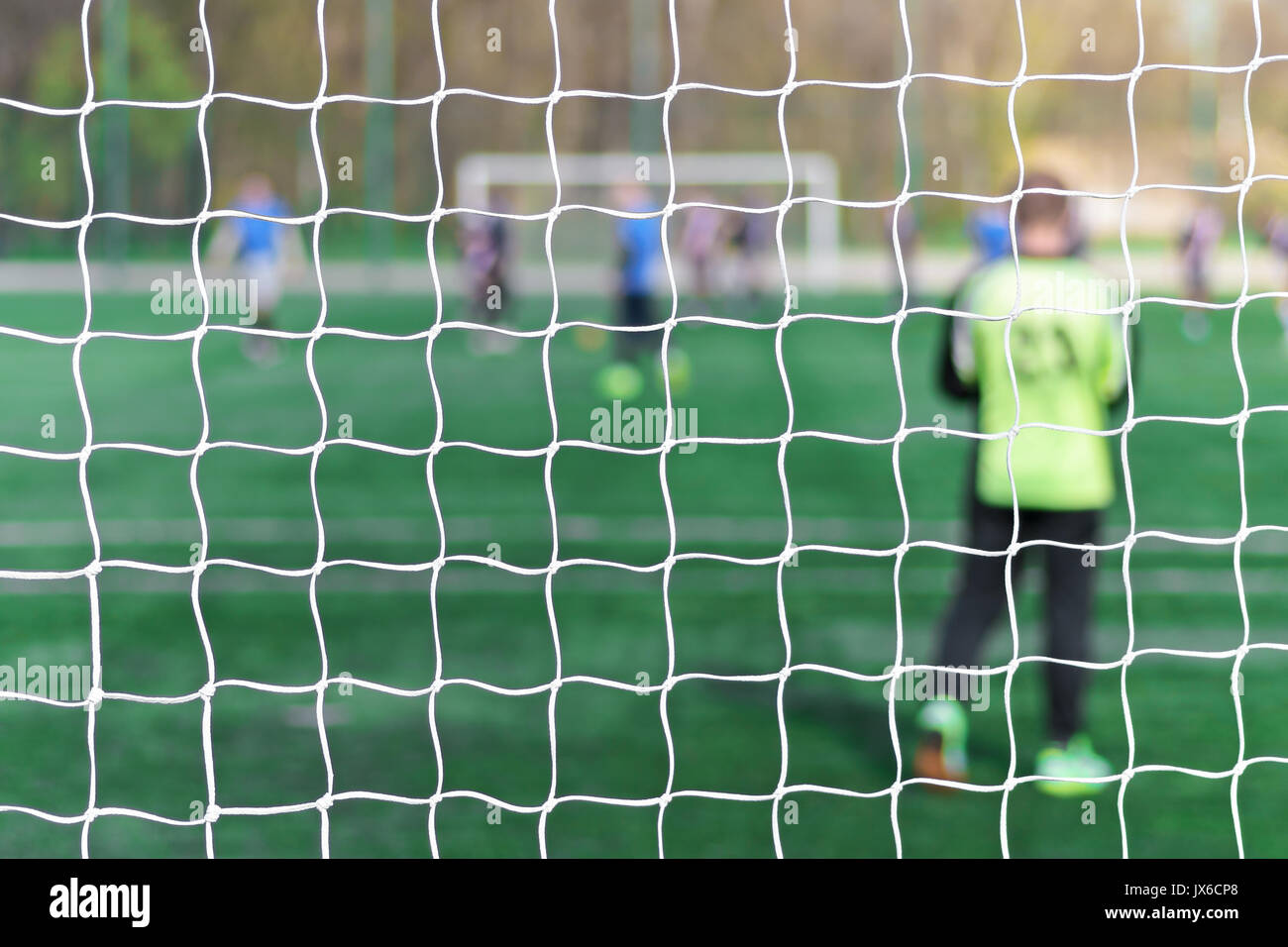 Torhüter steht gegen Ziel mit Net und Stadion. Fußball Tor net. Fußball Tor net. In verschwommenen Hintergrund stehen einem Torwart. Hinter dem Ziel der Spielgeschehen Stockfoto