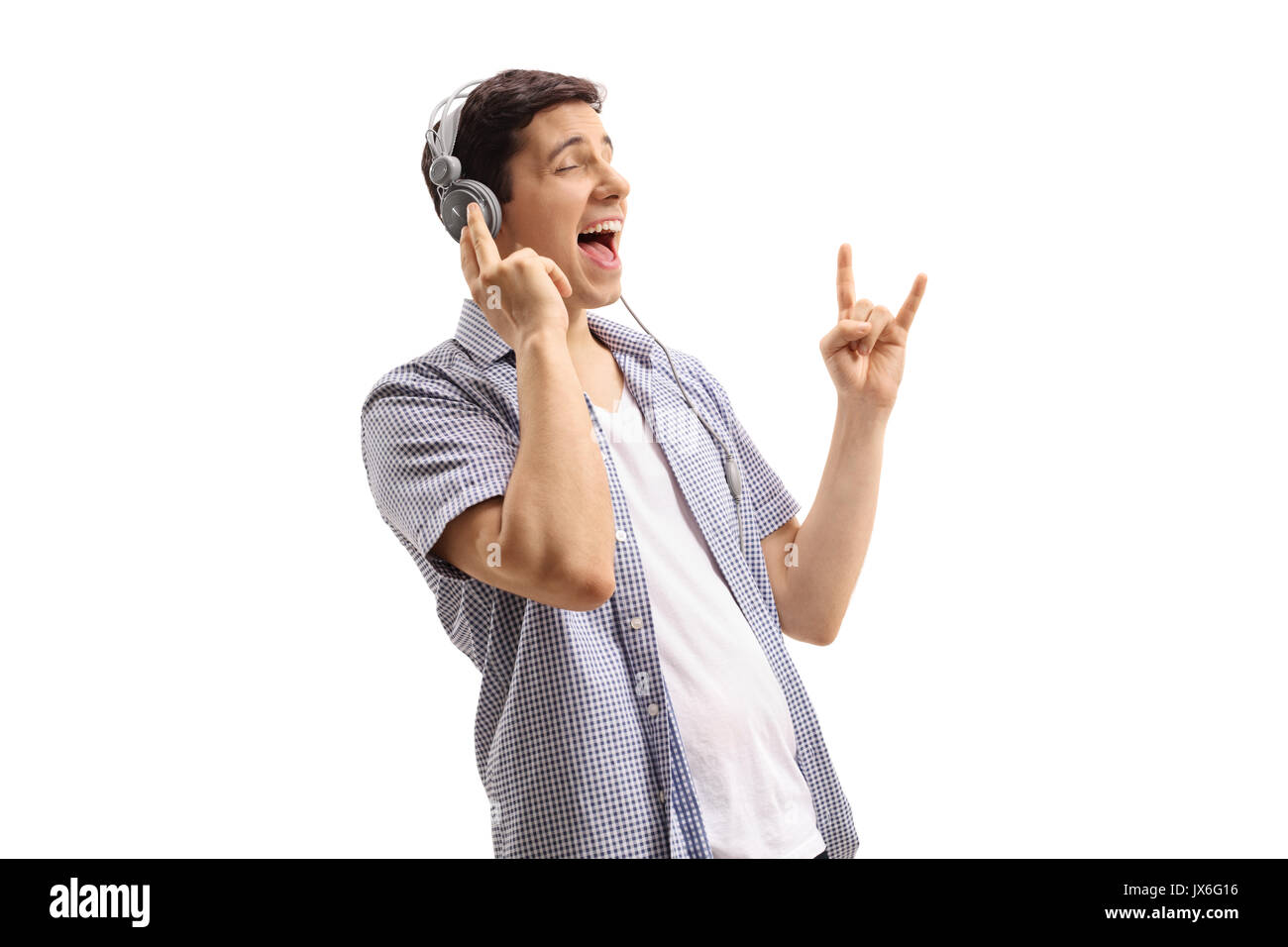Junger Mann Hören von Musik über Kopfhörer und einen Rock Geste auf weißem Hintergrund Stockfoto