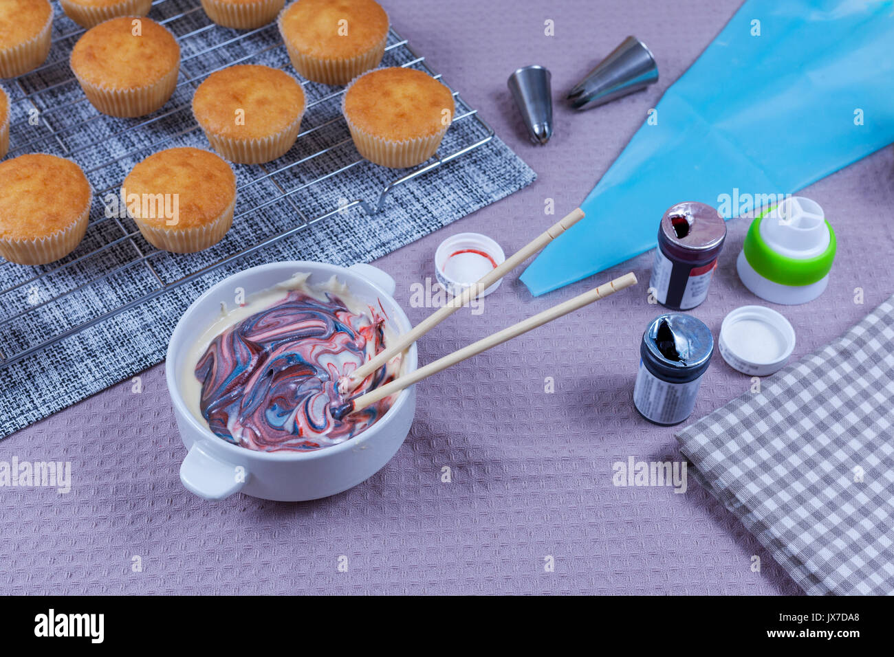 Frische hausgemachte Kuchen auf einem Backblech mit einer Schüssel mit bunten buttercream bereit auf den Kuchen geleitet zu werden. Stockfoto