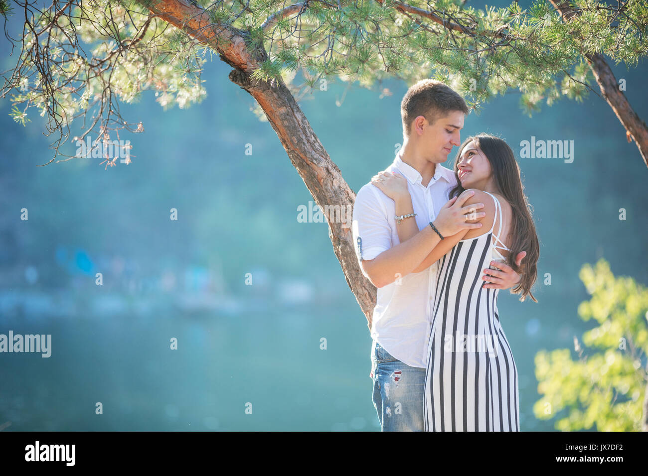 Romantische junge Paare gehen zu küssen, während unter ständigen Pine Tree Stockfoto