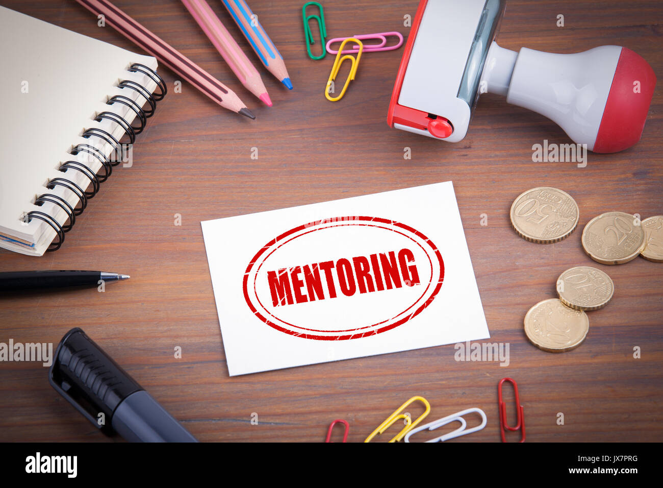 Mentoring Stempel. Holz- Schreibtisch mit Briefpapier, Geld und einen Notizblock. Stockfoto