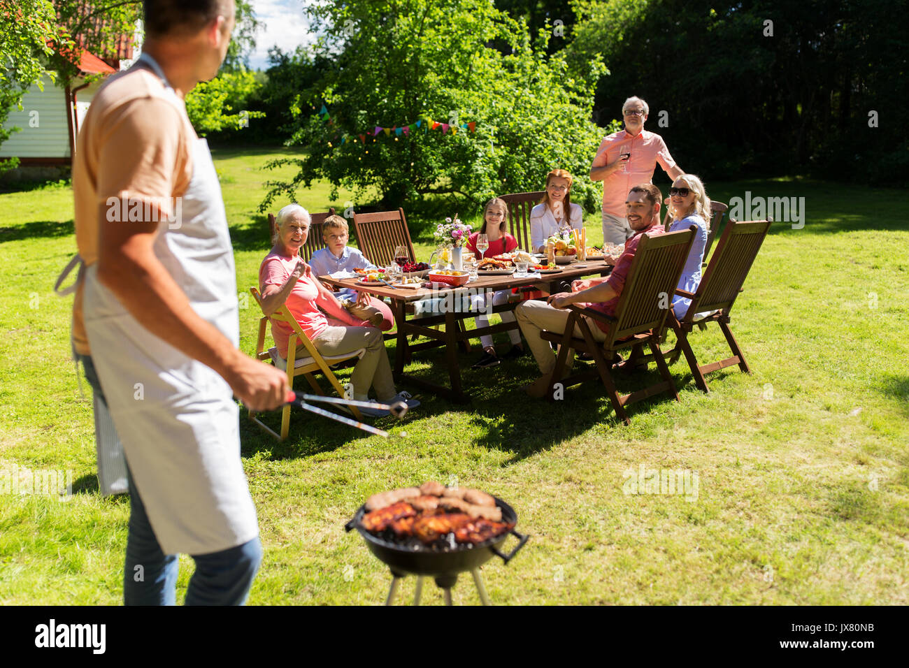 Mann, Kochen von Fleisch auf Grill am Sommerfest Stockfoto