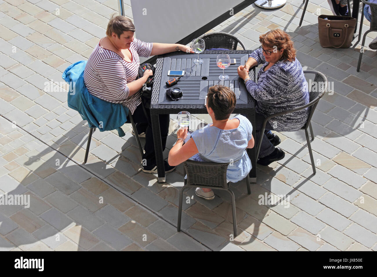 3 Damen entspannen und Cocktails im Sonnenschein saß an einem Tisch draußen an der Bar. Stockfoto