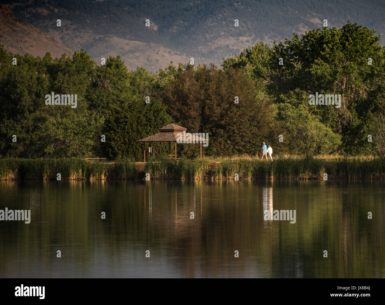 Ein älteres Ehepaar einen morgendlichen Spaziergang rund um einen See mit Reflektion Stockfoto