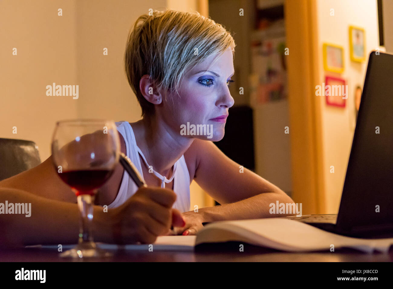 Frau Notizen vom Laptop, während Sie trinken Wein Stockfoto