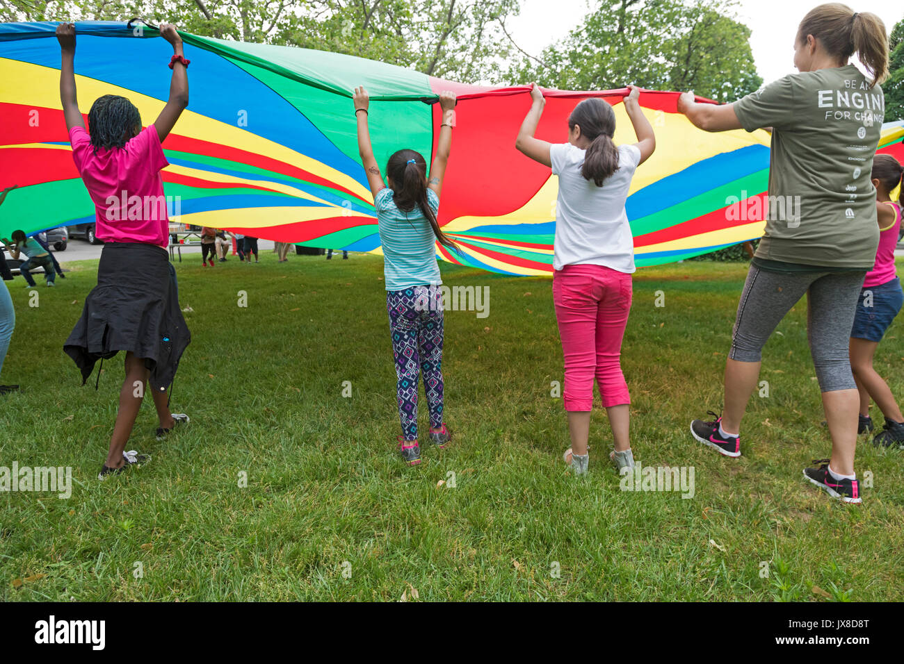 Detroit, Michigan - Kinder spielen mit einem großen Fallschirm Tuch in der Clark Park. Stockfoto