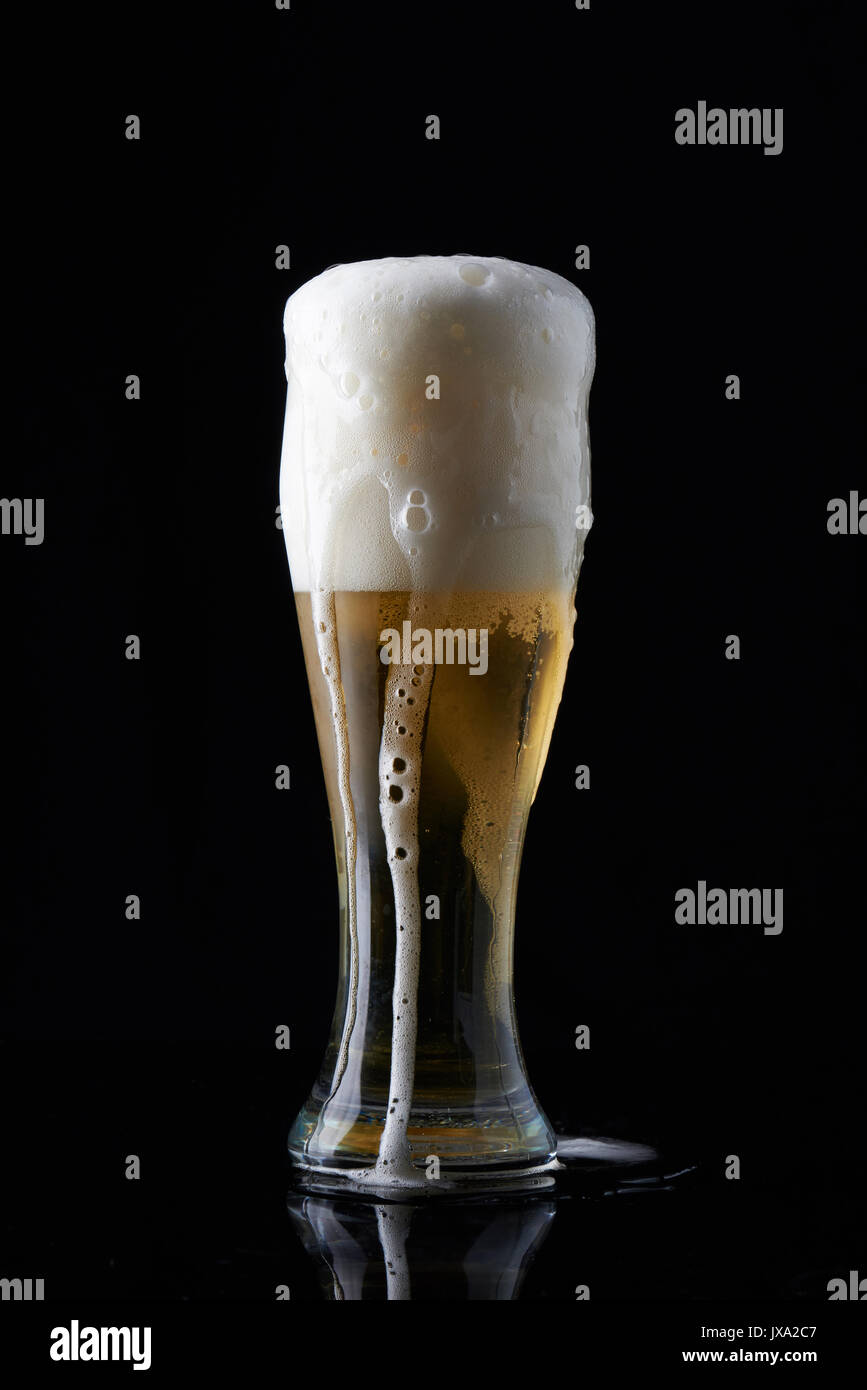 Kaltes Bier in großen Glas auf schwarzem Hintergrund Stockfoto