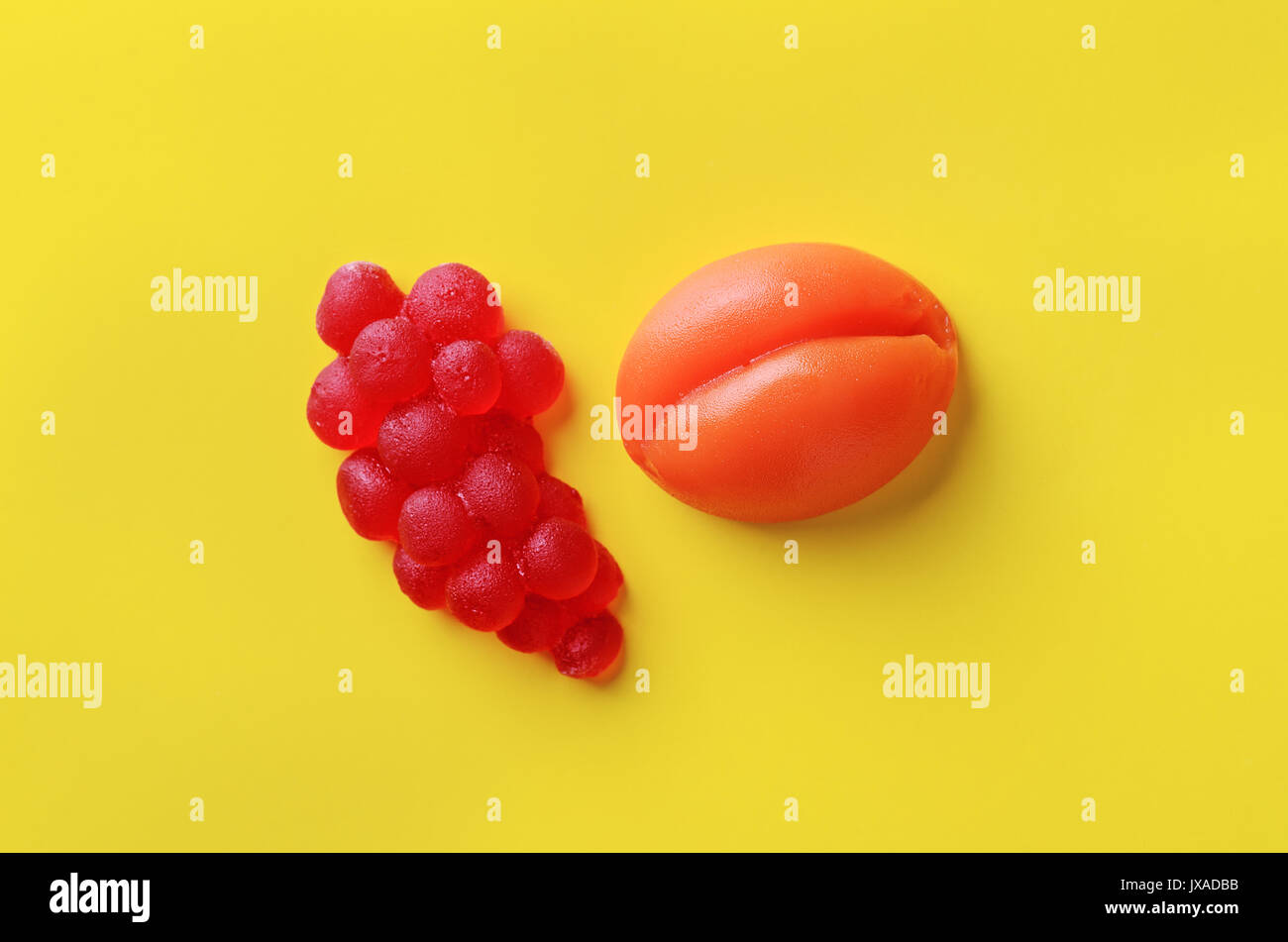 Aprikose und Beeren süße Marmelade candy auf gelben Hintergrund, Ansicht von oben. Trendy buntes Foto. Minimalistischer Stil mit bunten Papier Kulisse. Flach Stockfoto