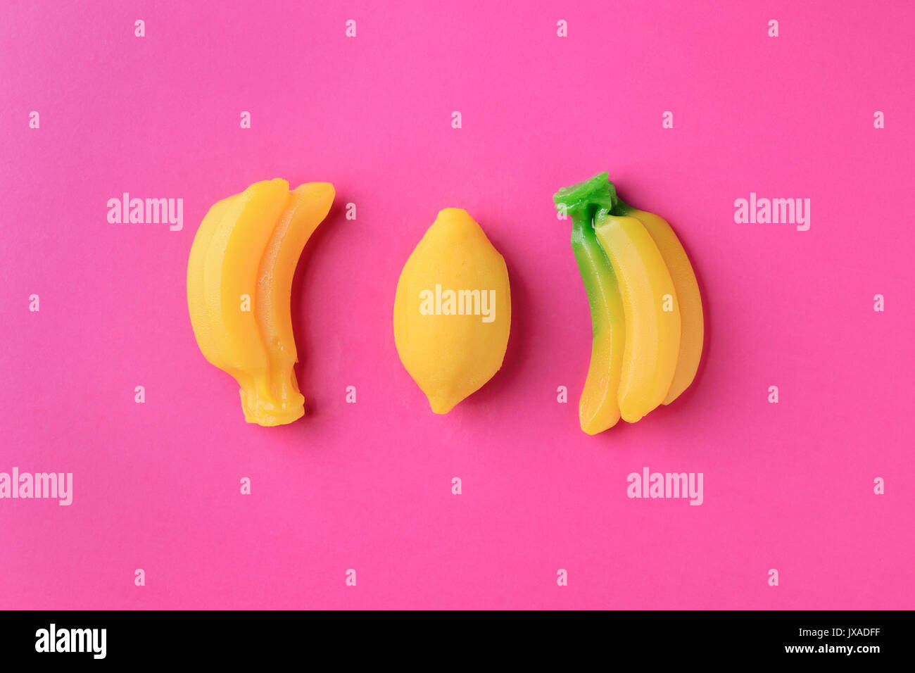 Zitronen und Bananen süße Marmelade candy auf rosa Hintergrund, Ansicht von oben. Trendy buntes Foto. Minimalistischer Stil mit bunten Papier Kulisse. Flach fashi Stockfoto