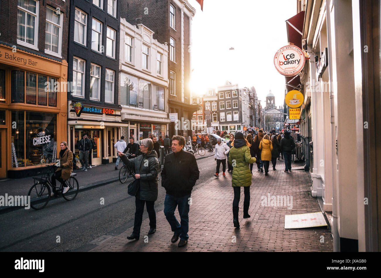 Amsterdam, Niederlande - 25 April 2017: Touristische Spaziergang entlang einer engen Straße im historischen Zentrum von Amsterdam bei Sonnenuntergang. Stockfoto