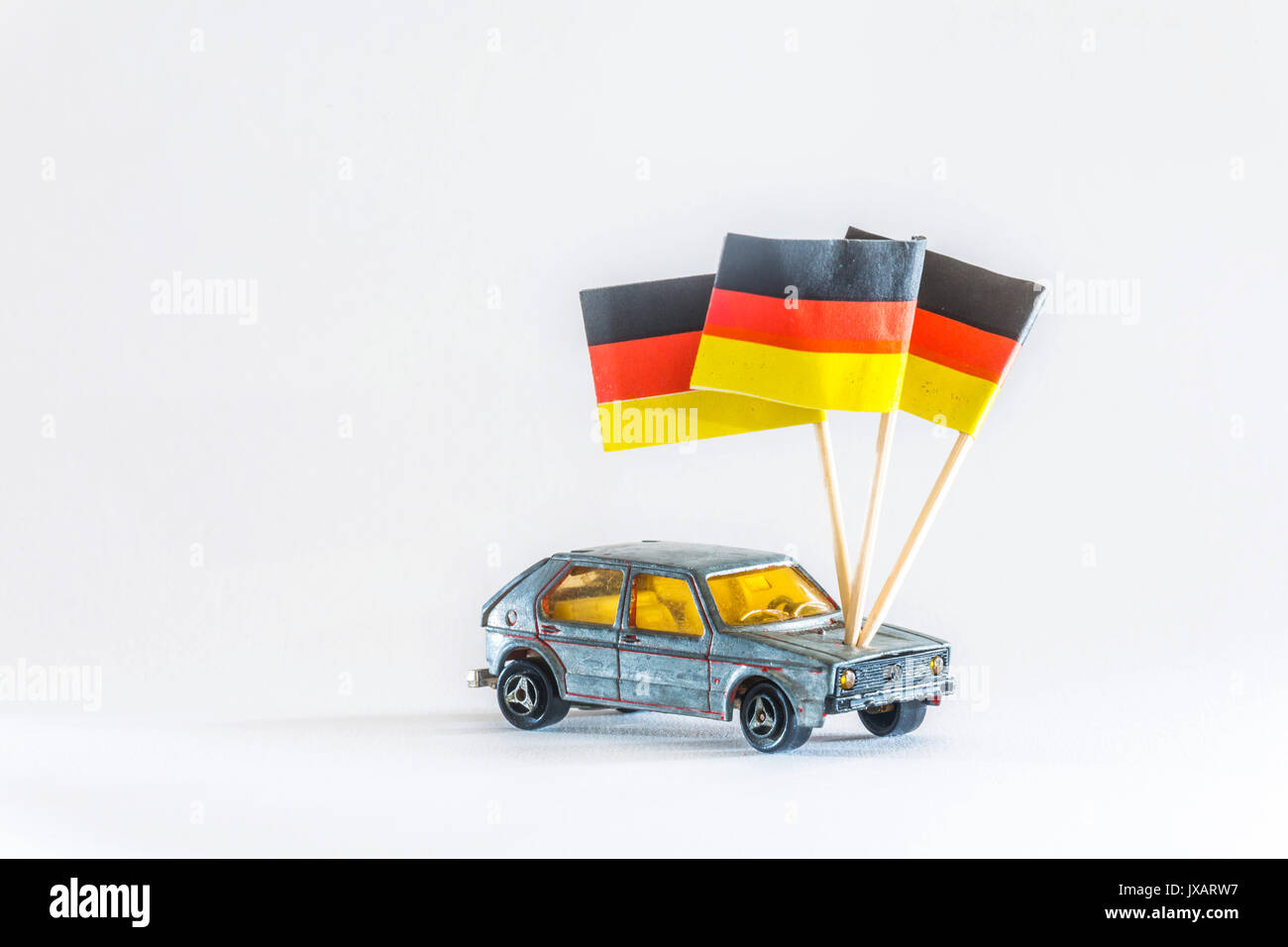 Modellauto. Ein spielzeugauto der Marke Volkswagen VW Golf, leicht demoliert. Mit Deutschlandflagge, Made in Germany. Stockfoto
