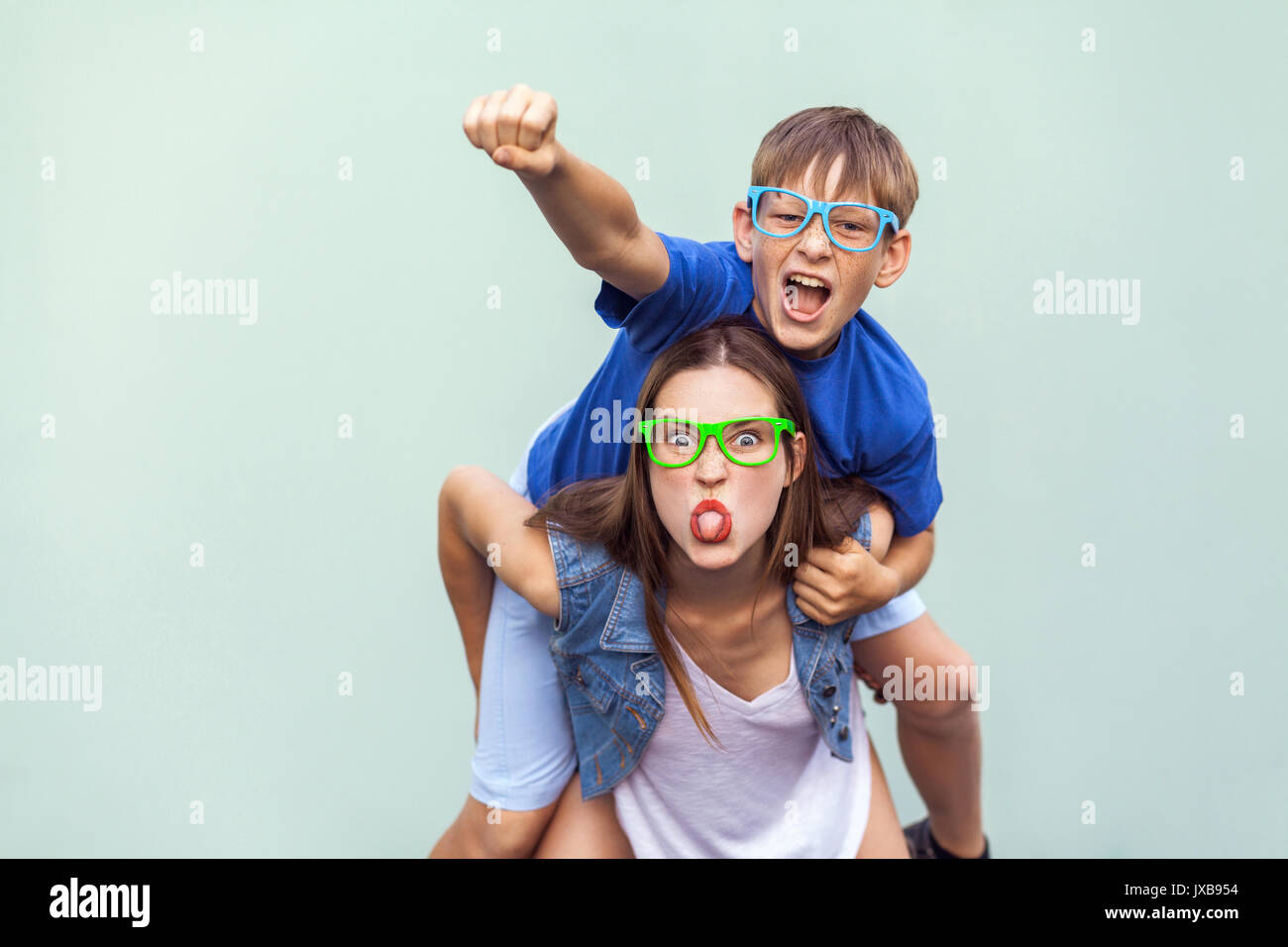 Crazy Emotionen und Gefühle. Super mann Stil! Die sommersprossige Bruder kletterte bis auf der Rückseite der älteren netten Schwester. Sie lustig, verrückt, im Gesicht, der Zunge, Stockfoto