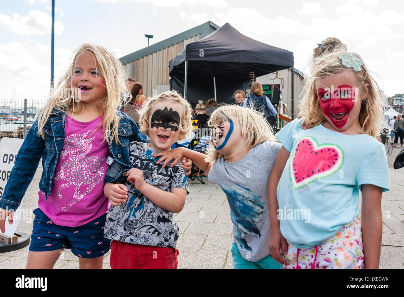 Vier Kaukasischen jungen Kinder, Mädchen, 6-7 Jahre alt, stehen in der Linie posieren. Alle haben in verschiedenen Stilrichtungen gemalt. Fröhlich, lachend. Stockfoto