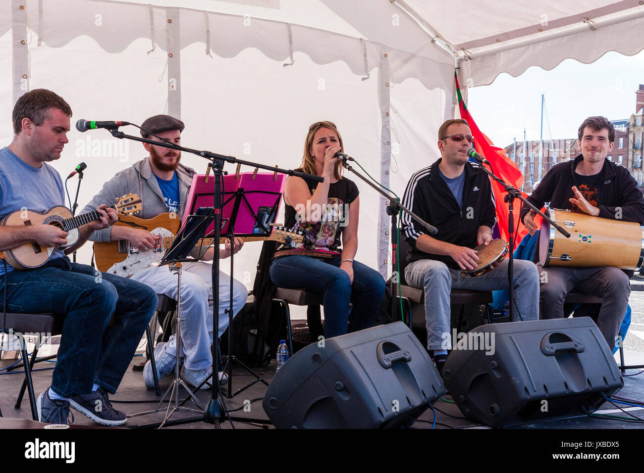 Fünf person Musik Gruppe Samba Azul sitzen auf kleinen Bühne während der ramsgate Festival. Gitarrist, Sänger, Schlagzeuger und Tamburin player. Stockfoto