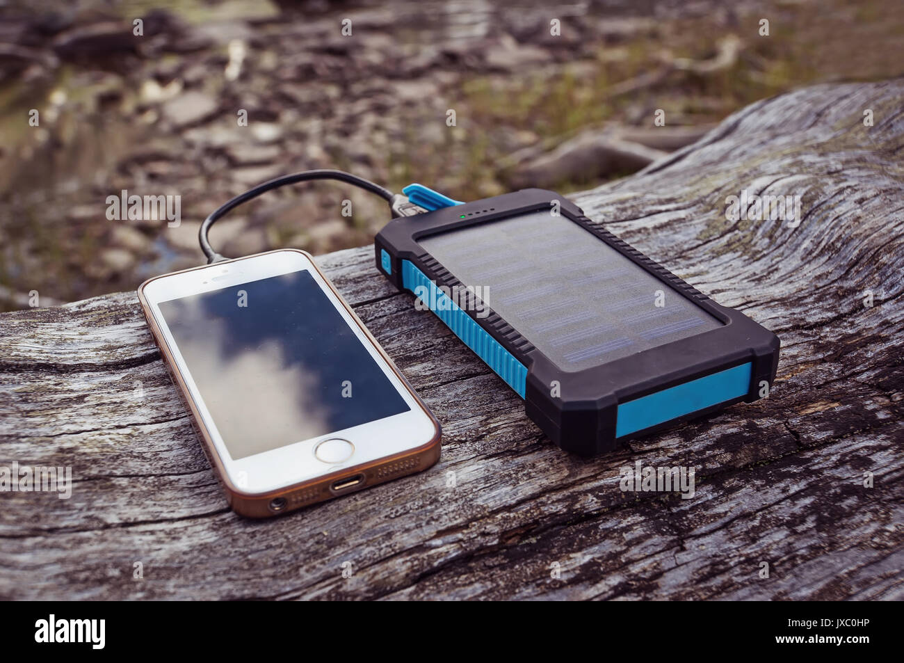 Solar Power Bank laden smart phone liegen auf einem Log Stockfoto