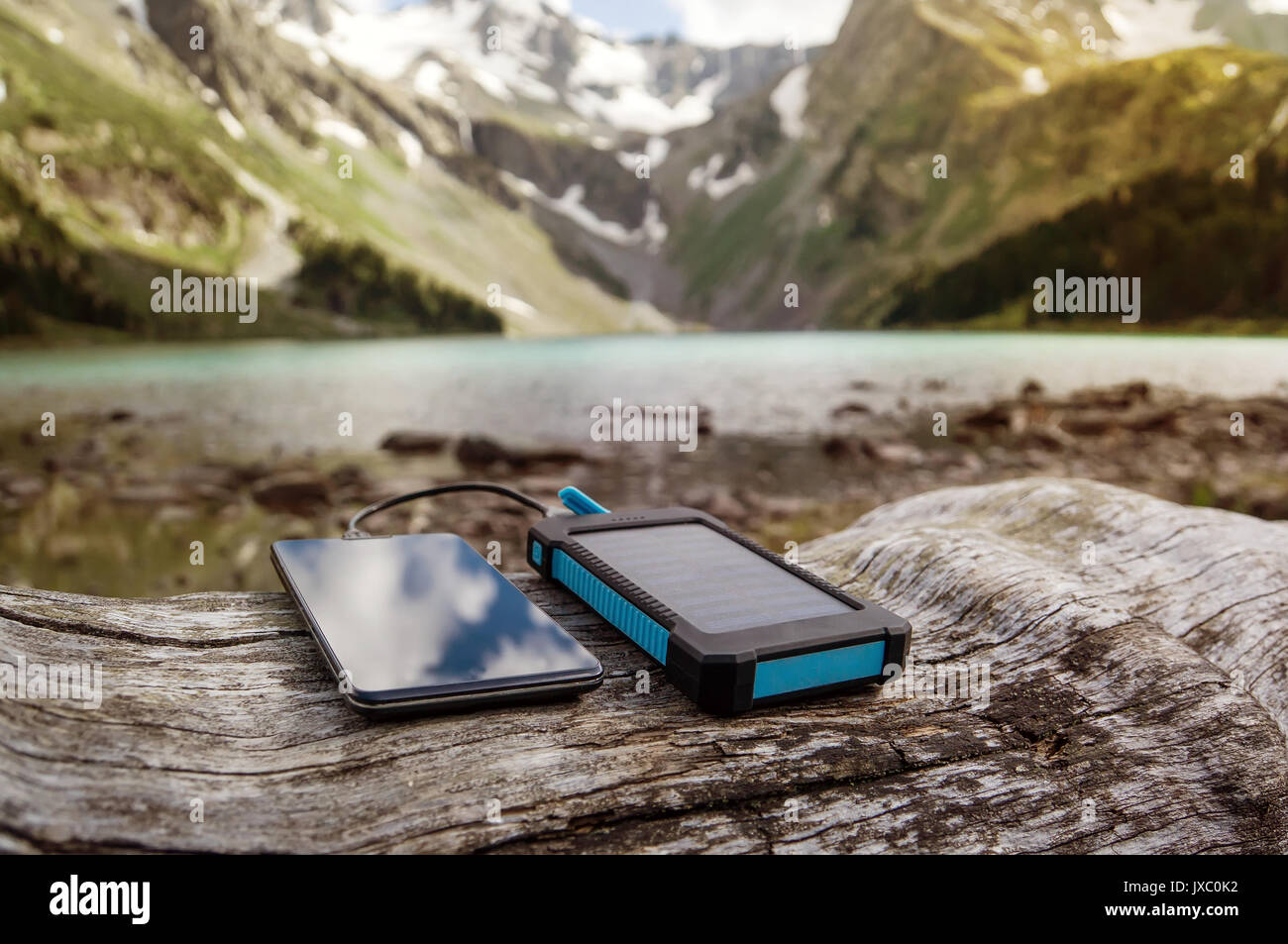 Akku Solar Energy Device auf dem Hintergrund der schönen Berglandschaft. Smart Phone aus der Solar Batterie aufladen. Stockfoto