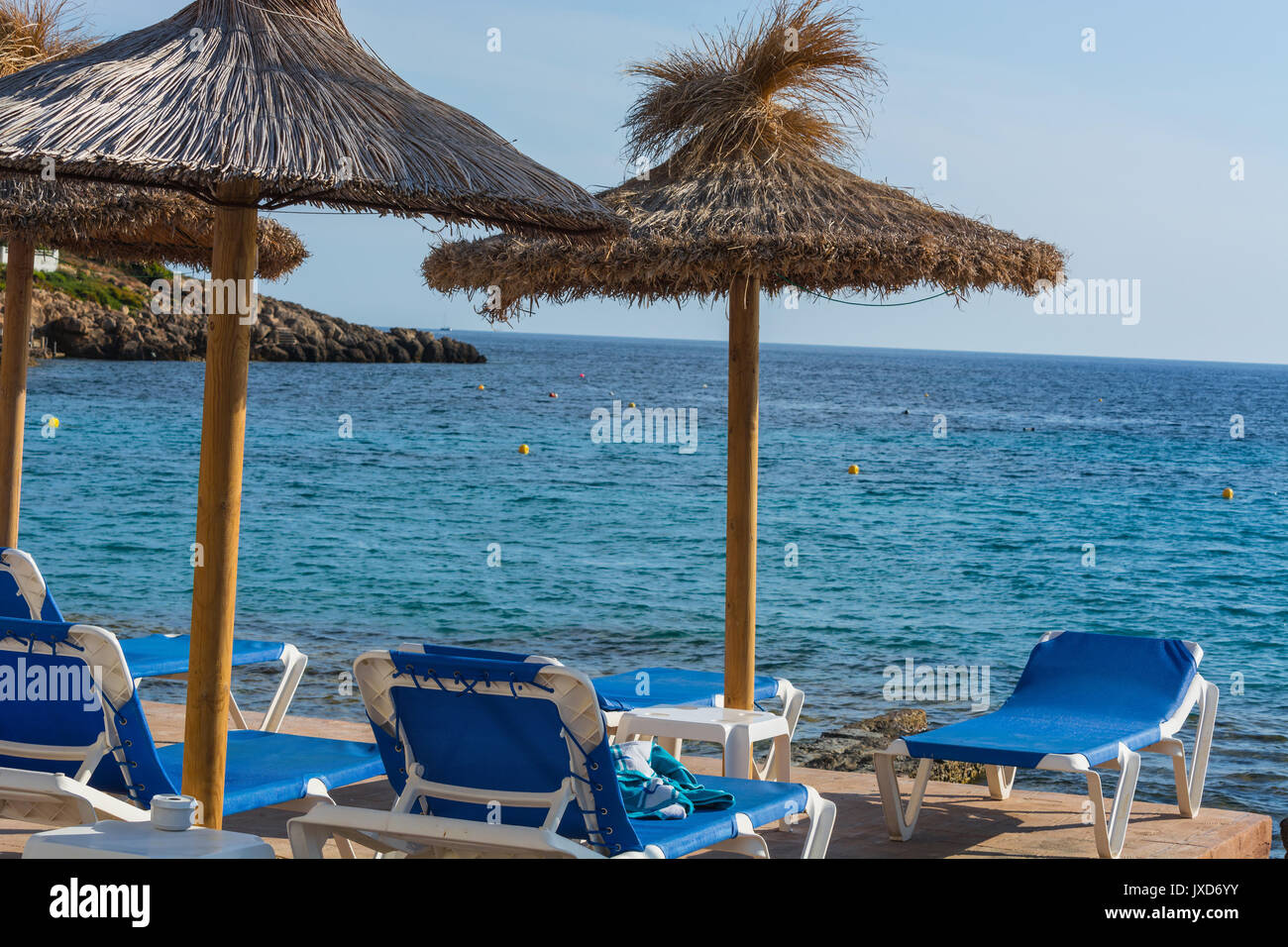 Blaues Meer und Sandstrand mit Liegestühlen und Sonnenschirmen. Stockfoto