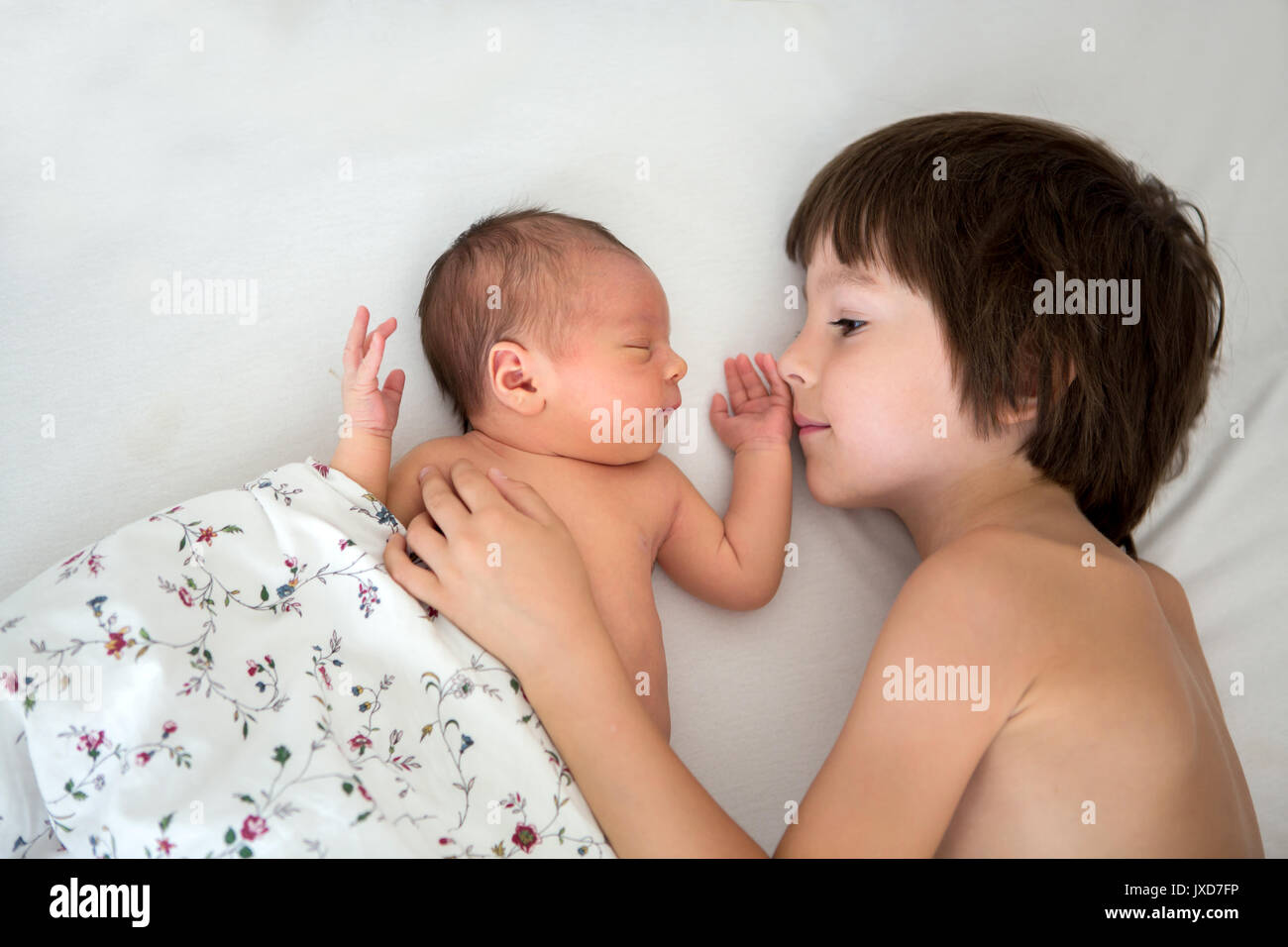 Schöne junge, umarmen mit Zärtlichkeit und sein neugeborenes Baby Bruder Pflege zu Hause. Familie Liebe Glück Konzept Stockfoto