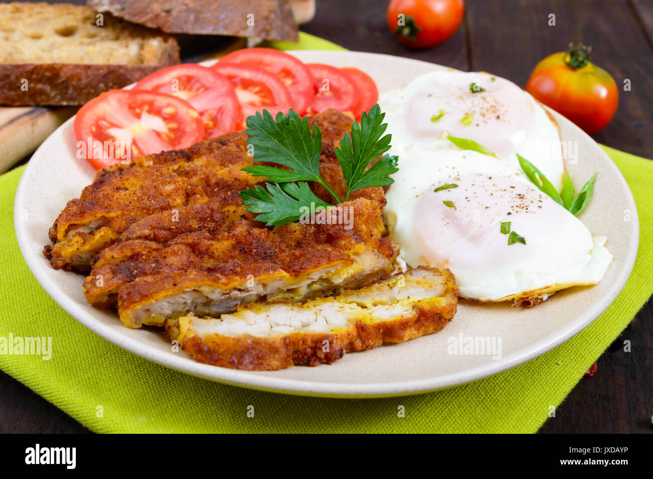 Stücke von Chop (Schnitzel), Toast mit Eiern, frischen Tomaten auf einem dunklen Hintergrund. Stockfoto