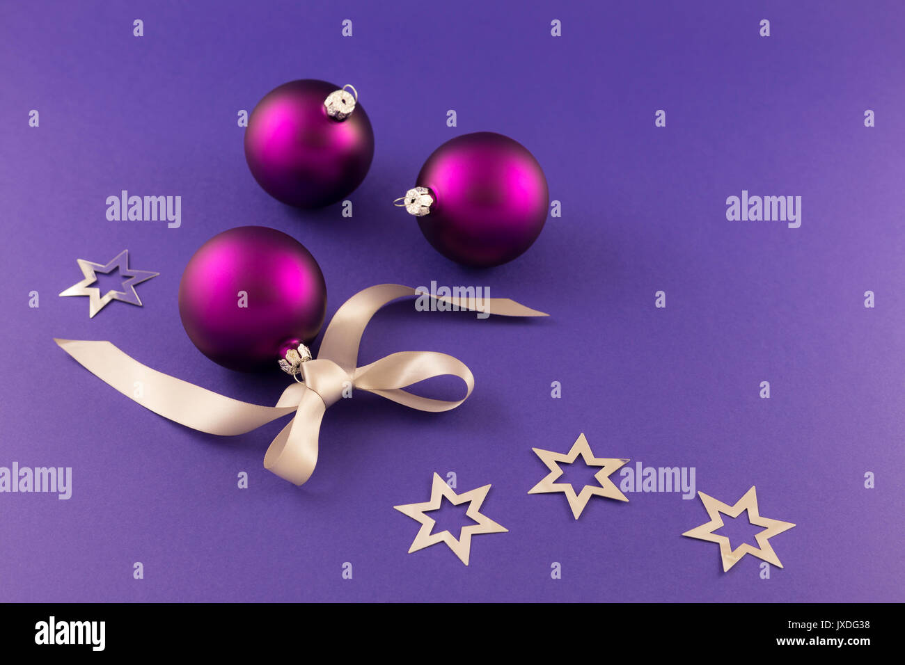 Schönen lila Weihnachtskugeln mit satin Wirkung, grau Geschenkband und metallic silber Sterne auf lila Hintergrund. Stockfoto