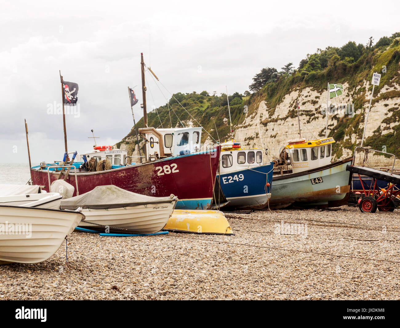 Küstenfischerei Boote mitgeführt und am Kiesstrand bei Bier, Devon, UK an einem stürmischen Juli Tag mit Hummer Töpfe und Fanggeräte für den Einsatz bereit. Stockfoto