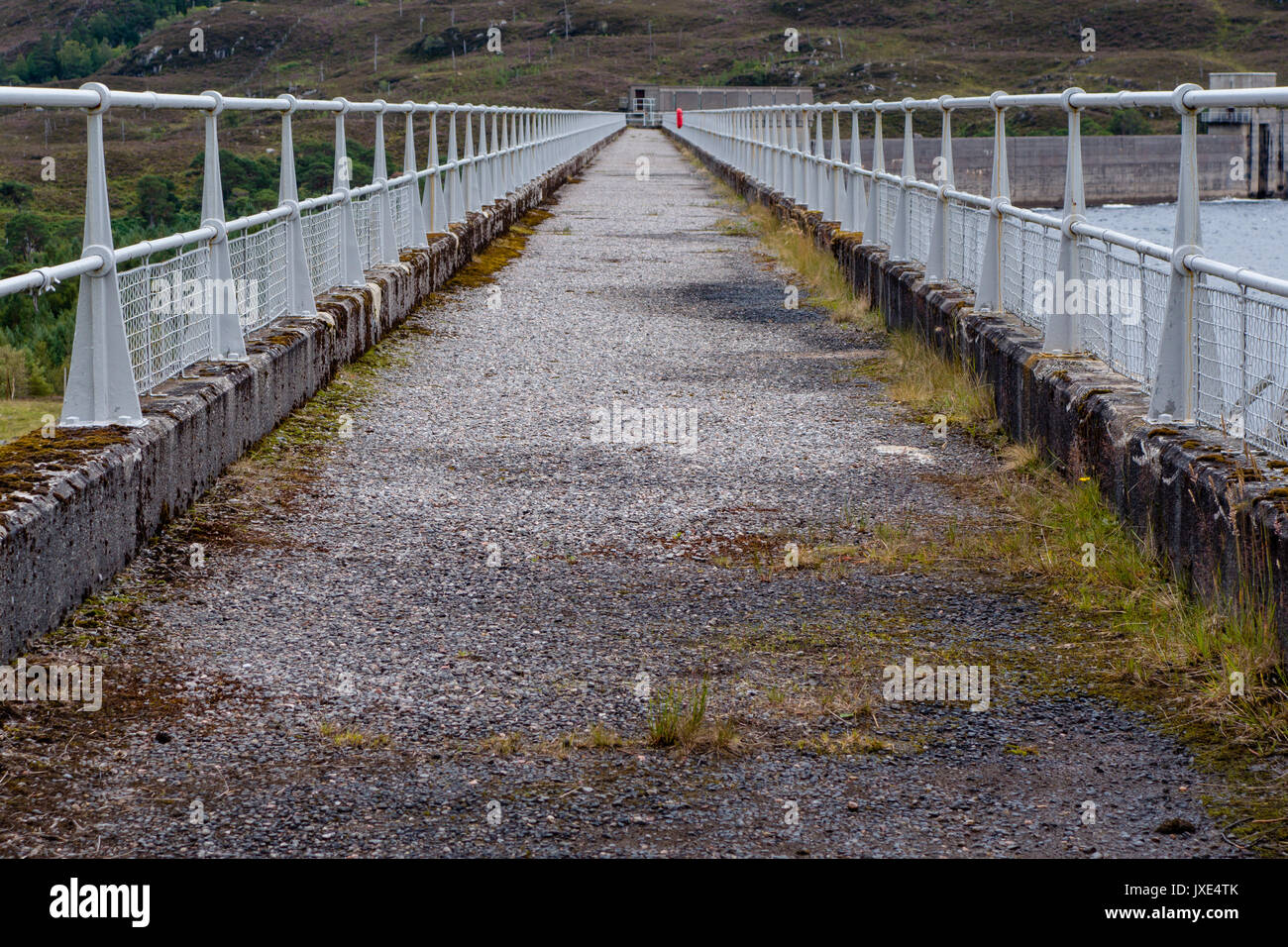 Beton Gehweg auf der Oberseite des Wasserkraftwerk Staumauer in den schottischen Highlands auf Überlauf Punkt mit weißem Metall Geländer auf beiden sid Führenden führen Stockfoto