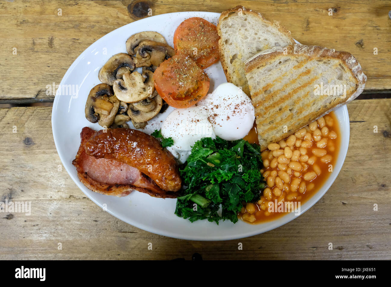Eine gesunde Alternative zum herkömmlichen Englisches Frühstück mit pochierten Eiern, Tomaten, Wurst, Speck, Pilzen und Kale Stockfoto