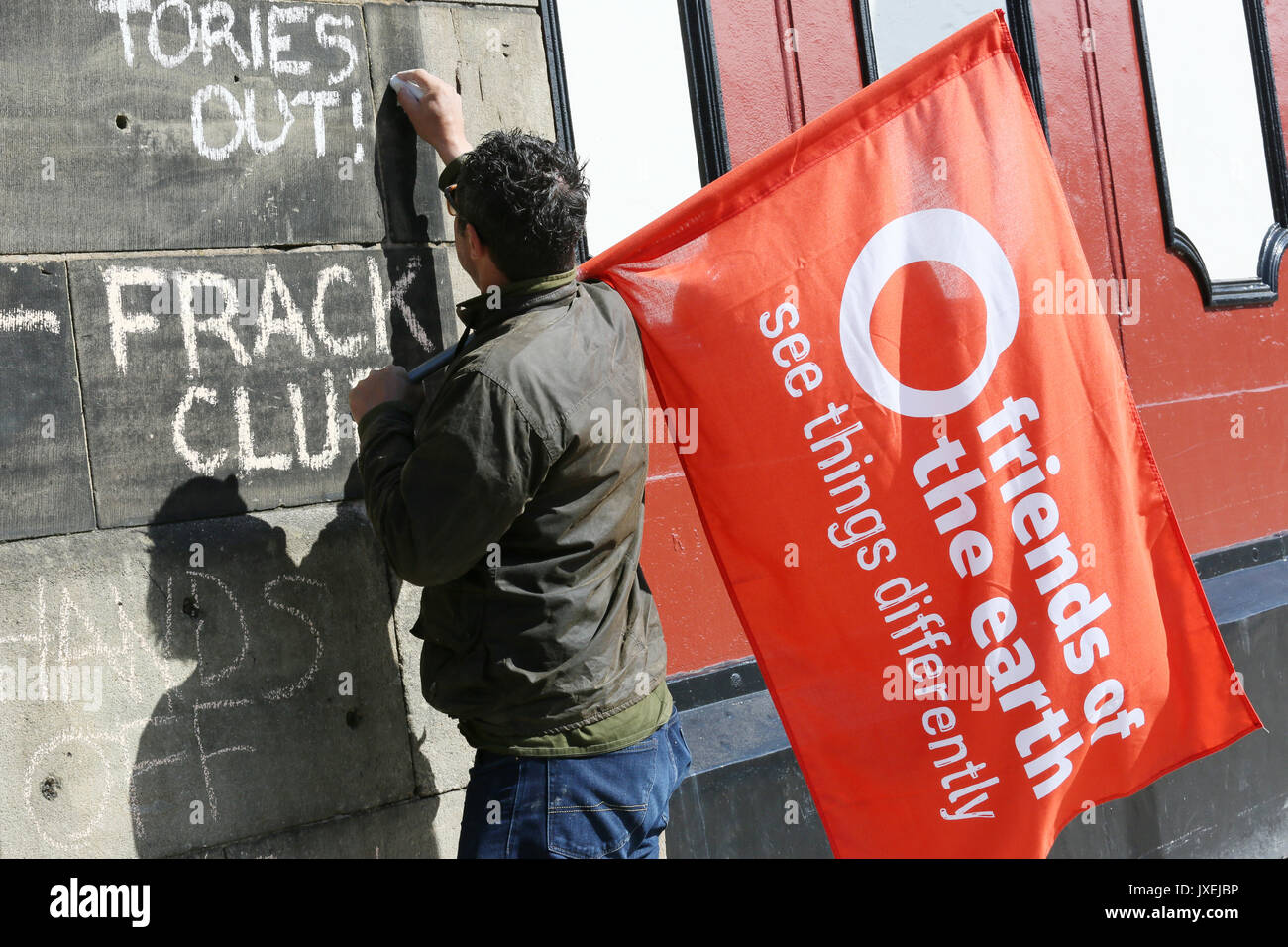 Preston, Großbritannien. 16 Aug, 2017. "Tories" geschrieben wurden an einer Wand mit Kreide durch ein Anti fracking Mitkämpfer im Besitz einer Flagge mit "Freunde der Erde sehen die Dinge anders" aufgedruckt, Preston, 16. August 2017 (C) Barbara Cook/Alamy Live News Credit: Barbara Koch/Alamy leben Nachrichten Stockfoto