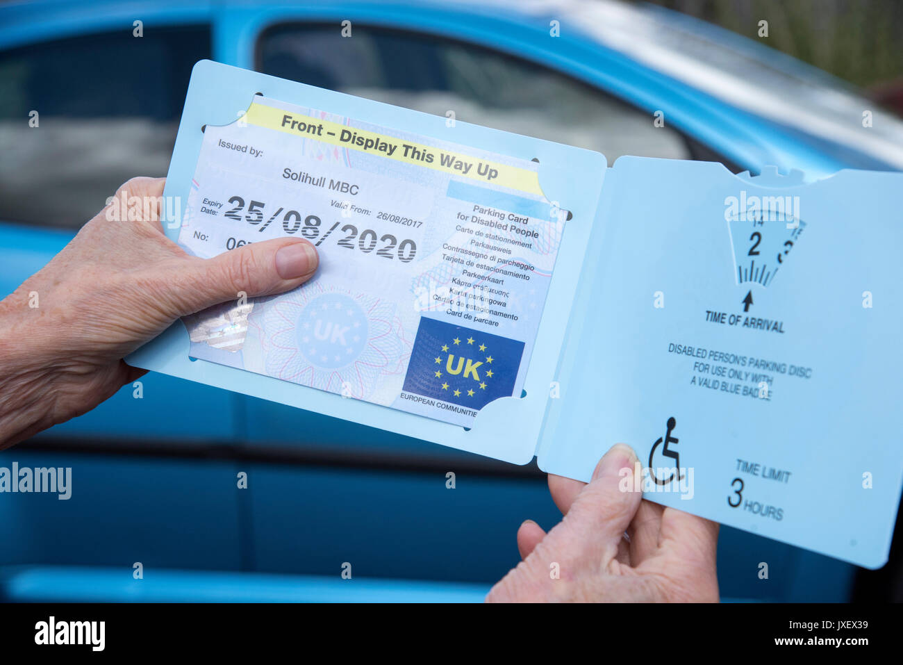 Woman's Hände halten ein Blue Badge Parkscheibe in Großbritannien für behinderte Fahrer. Stockfoto