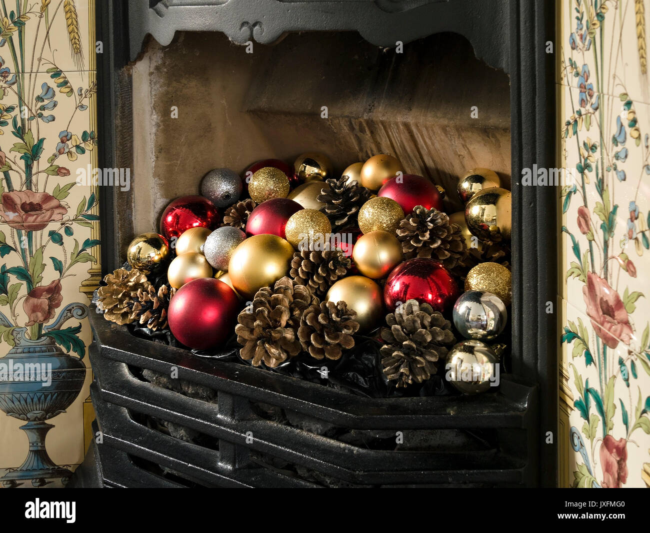 Hübscher, gusseiserner Kamin im viktorianischen Stil mit farbenfrohen Weihnachtskugeln und Tannenzapfen, England, Großbritannien Stockfoto