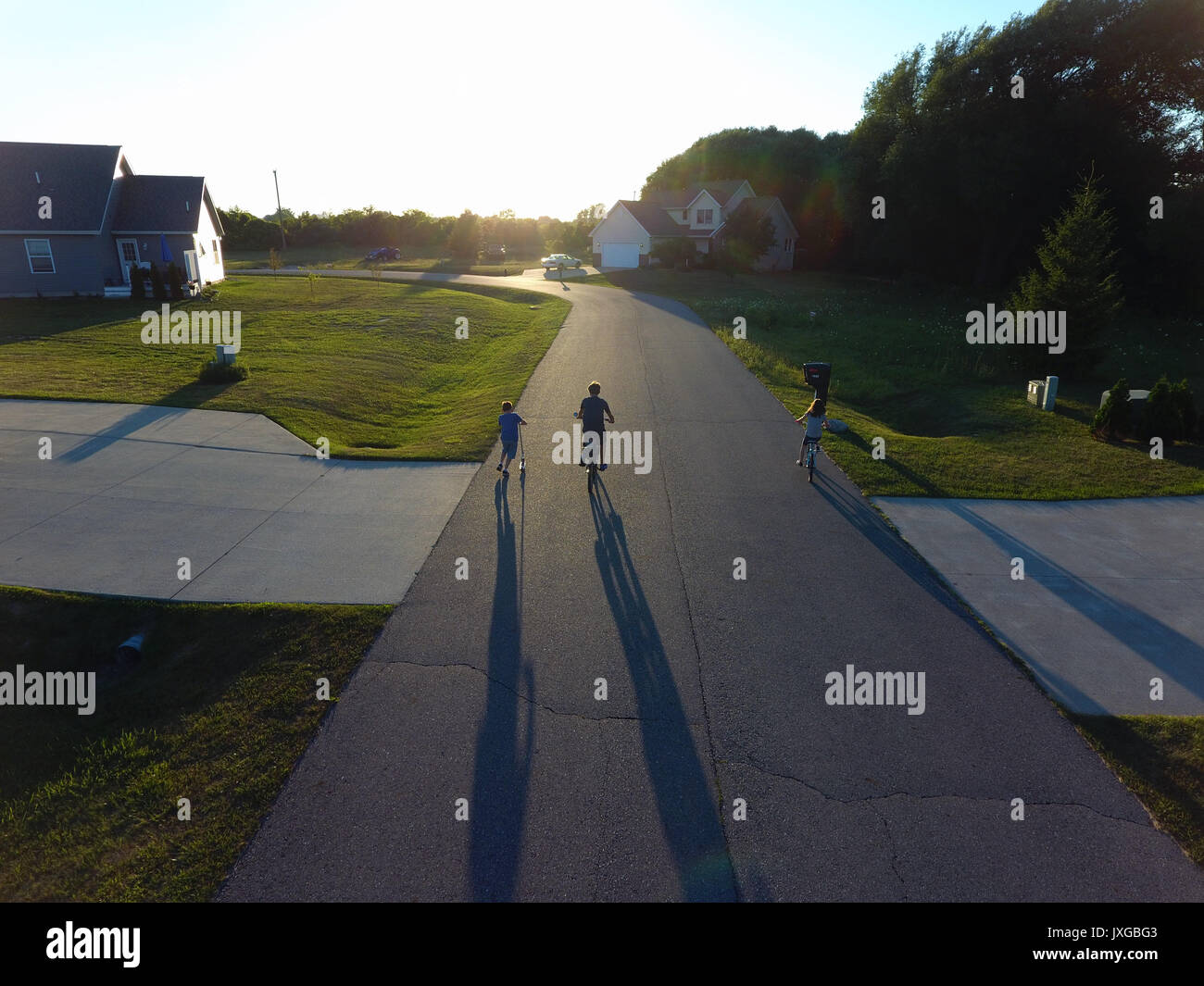 Kinder gehen Sie in Richtung Sonnenuntergang auf einer Straße werfen lange Schatten Stockfoto