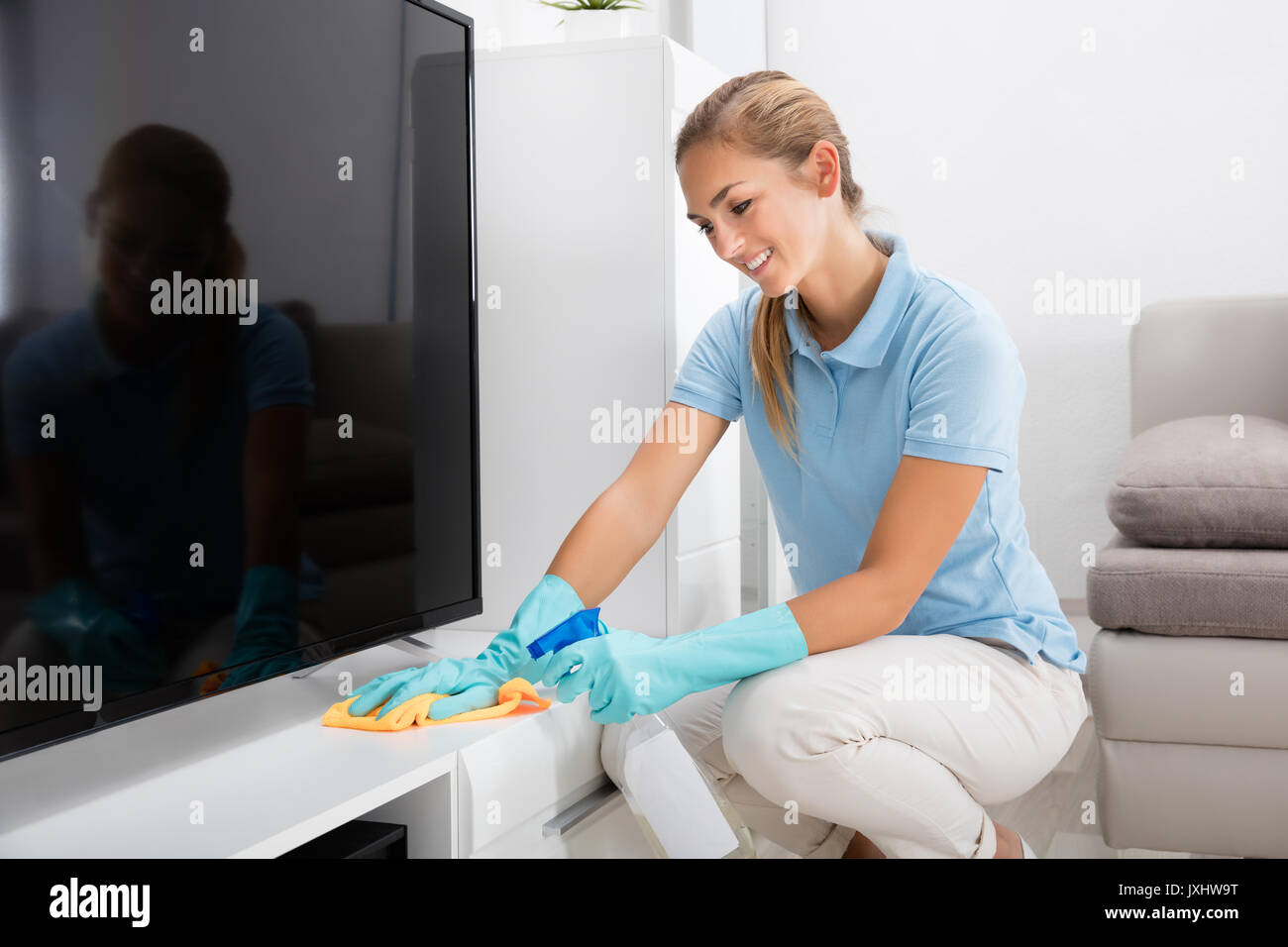 Junge Frau Reinigung der Möbel Wohnzimmer zu Hause Stockfoto