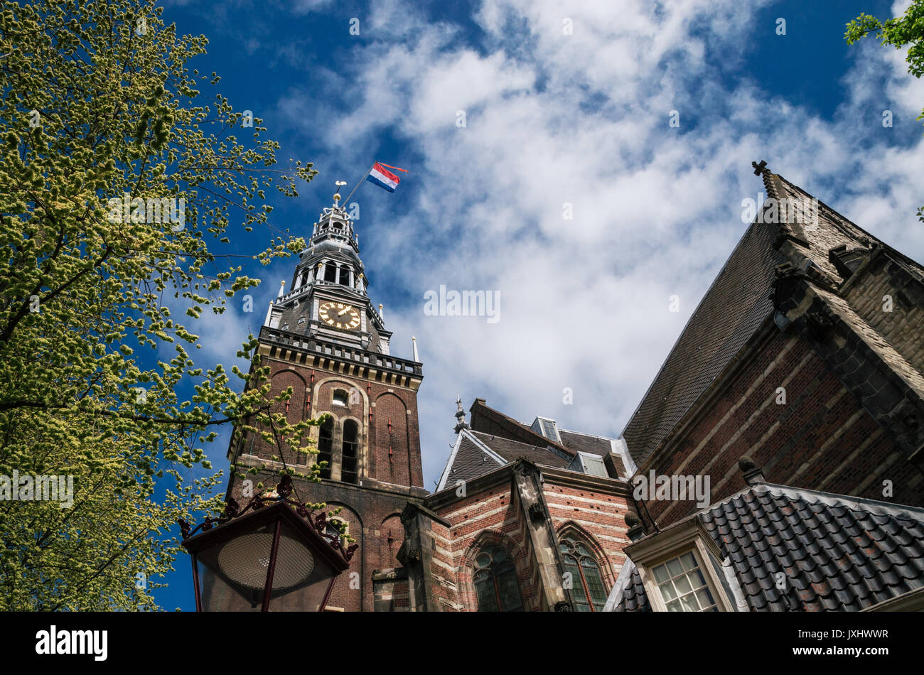 Turm der alten Kirche mit niederländischer Flagge im Zentrum von Amsterdam, Niederlande Stockfoto