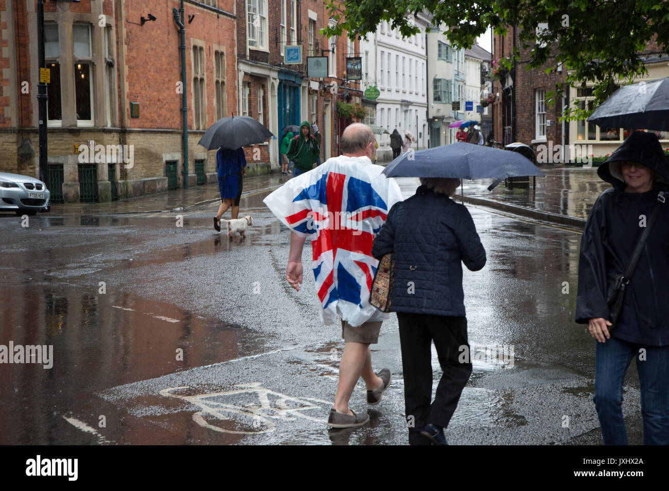 Sehr regnerischen Tag im Zentrum von York, Sonnenschirme und einen Mann, der in einer Union Flag anorak Poncho Stockfoto