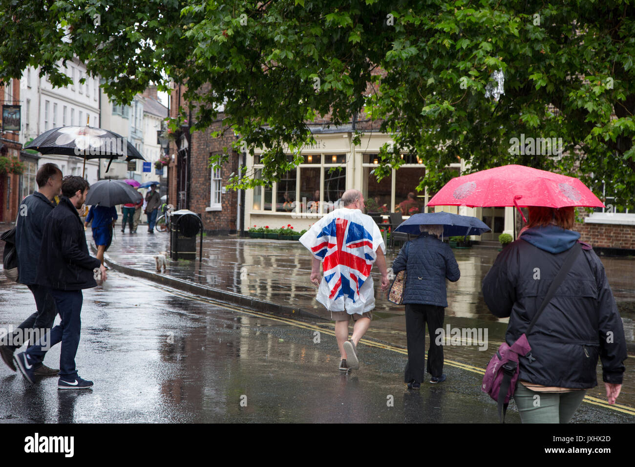 Sehr regnerischen Tag im Zentrum von York, Sonnenschirme und einen Mann, der in einer Union Flag anorak Poncho Stockfoto