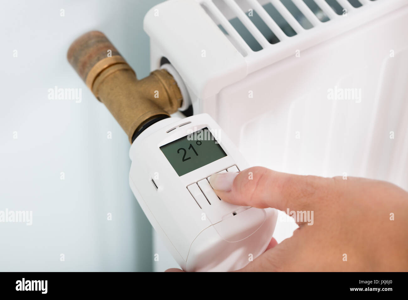 Person's Hand Einstellen der Temperatur am Thermostat zur Steuerung der Hitze in Zentralheizung Stockfoto